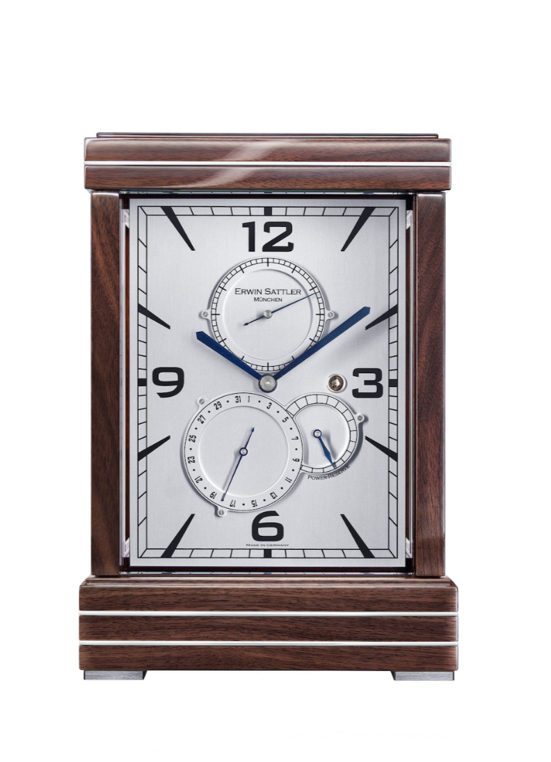 ERWIN SATTLER METRICA II.
Leverbaar in zwart gelakt of in Notenhout beide hoogglans gepolijst met metaal inleg, 27,5 cm hoog, 18,50 cm breed en 12 cm diep. Ontspiegeld mineraal glas. Uurwerk Sattler Kaliber 1385. Loopduur 15 dagen. Veer opwinding voorzien van een via een Schneck geregelde krachtsoverbrenging. Regelbaar Zwitsers Echappement. 12 Precisie kogellagers en 11 Robijn lagers. Wijzerplaat in zwart of zilver met datum aanduiding, gangreserve en seconde wijzer. Staal gepolijste wijzers bij de zwarte wijzerplaat of geblauwd stalen wijzers bij de zilveren wijzerplaat. 